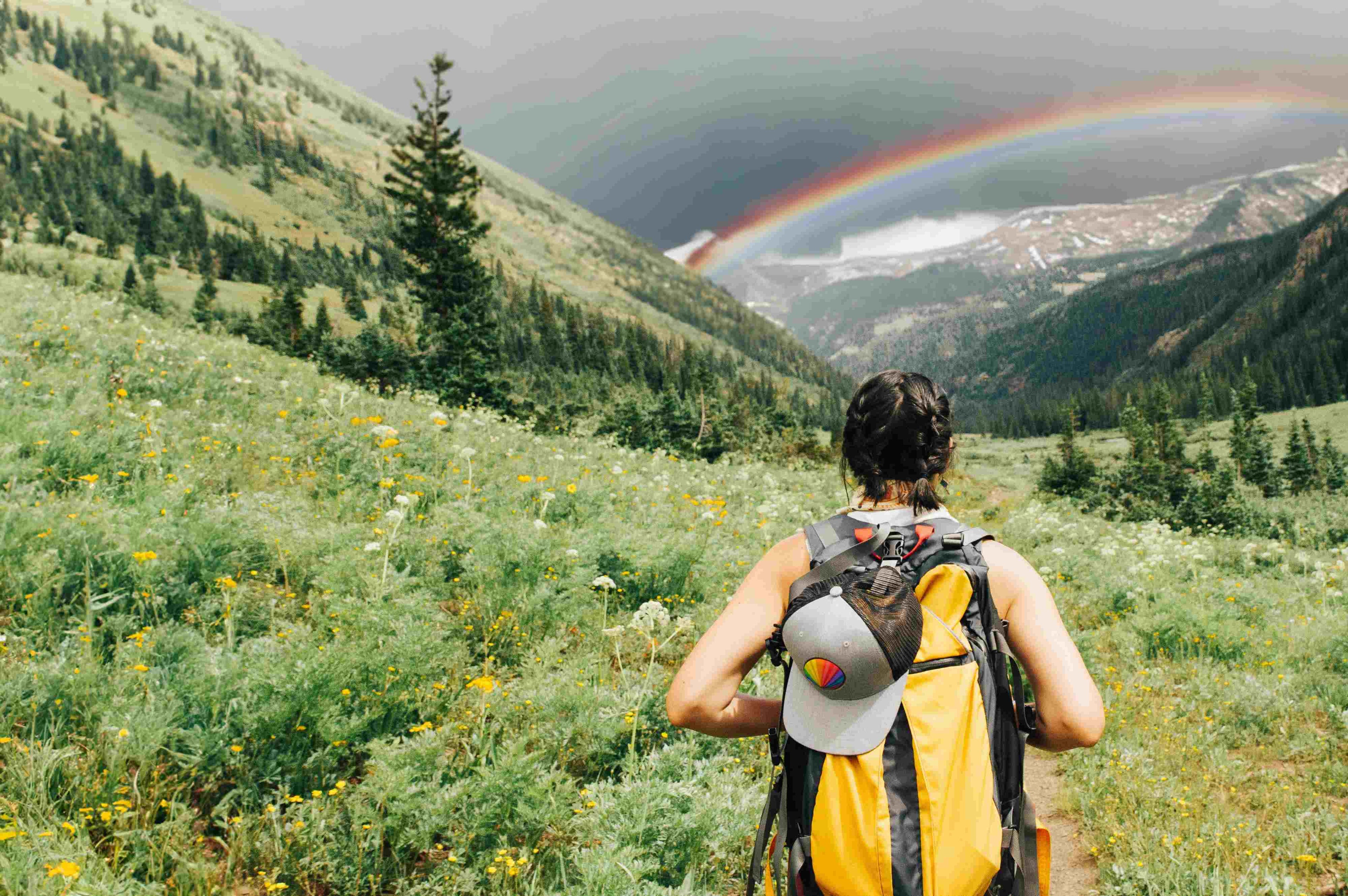 Woman hiking with a rainbow over mountains